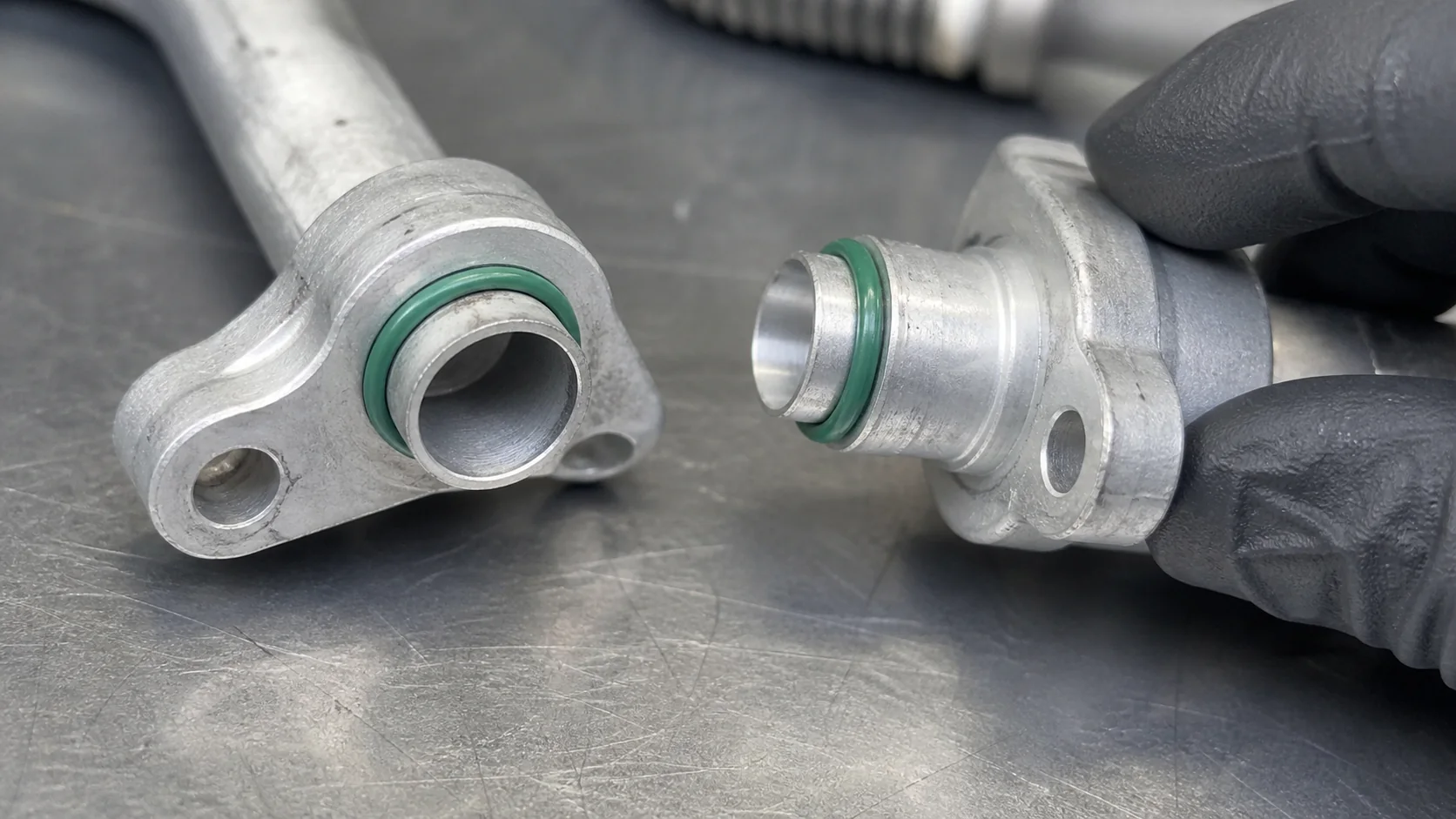 A/C line flange and O-ring seal being inspected before assembly