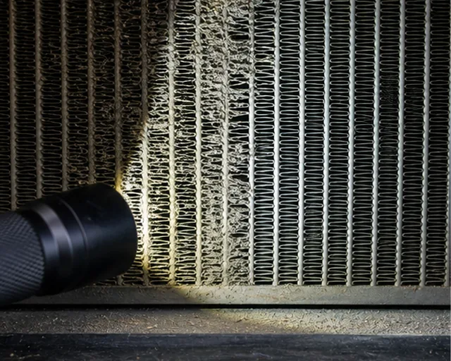 Flashlight inspection through blocked cooling fins to compare dirty and cleaned airflow areas