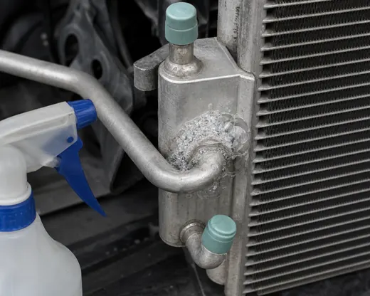 Soap bubbles forming at an AC condenser fitting during leak point confirmation